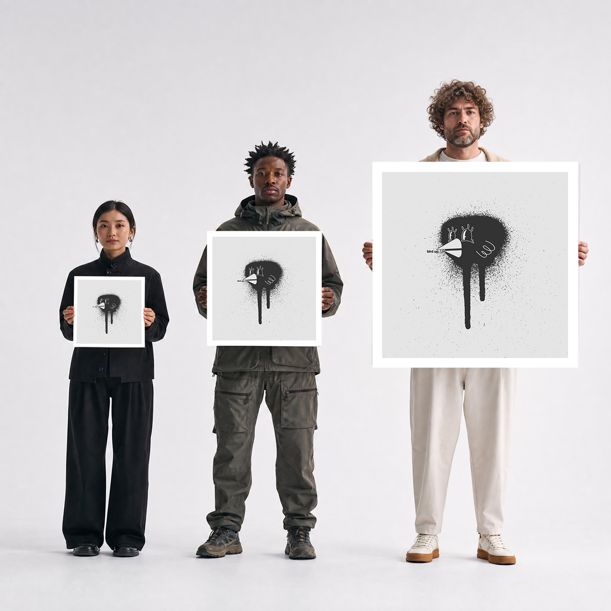 Scale comparison photo showing the 12x12, 20x20, and 40x40 print sizes of 'Bird' by Sunday Morning, held by three models for size reference.