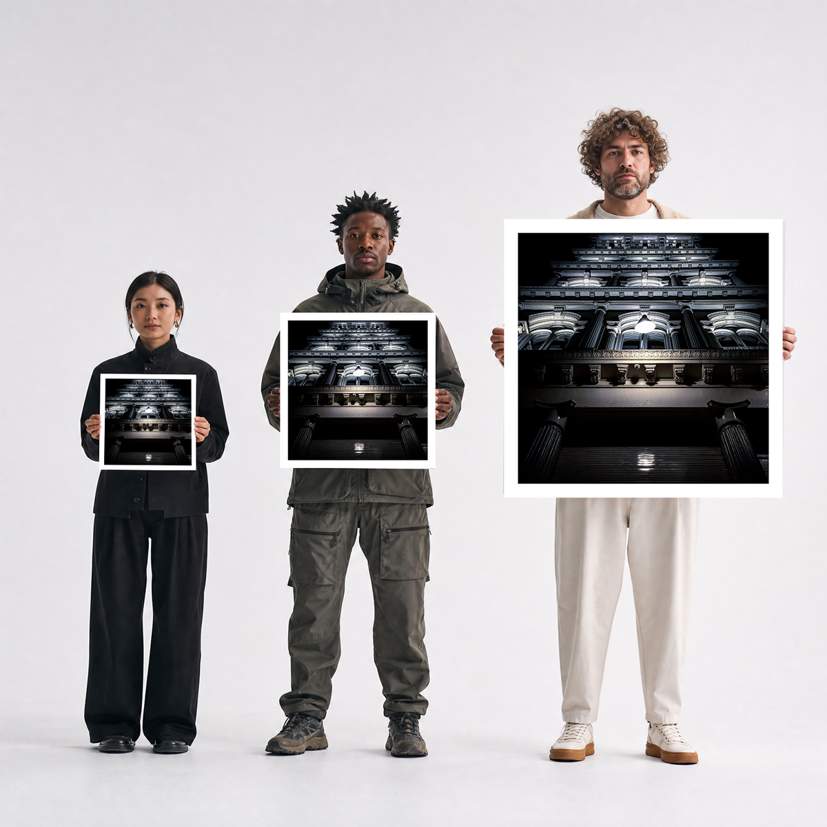 Scale comparison photo showing the 12x12, 20x20, and 40x40 print sizes of 'Ghost Dusters' by Sunday Morning, held by three models for size reference.