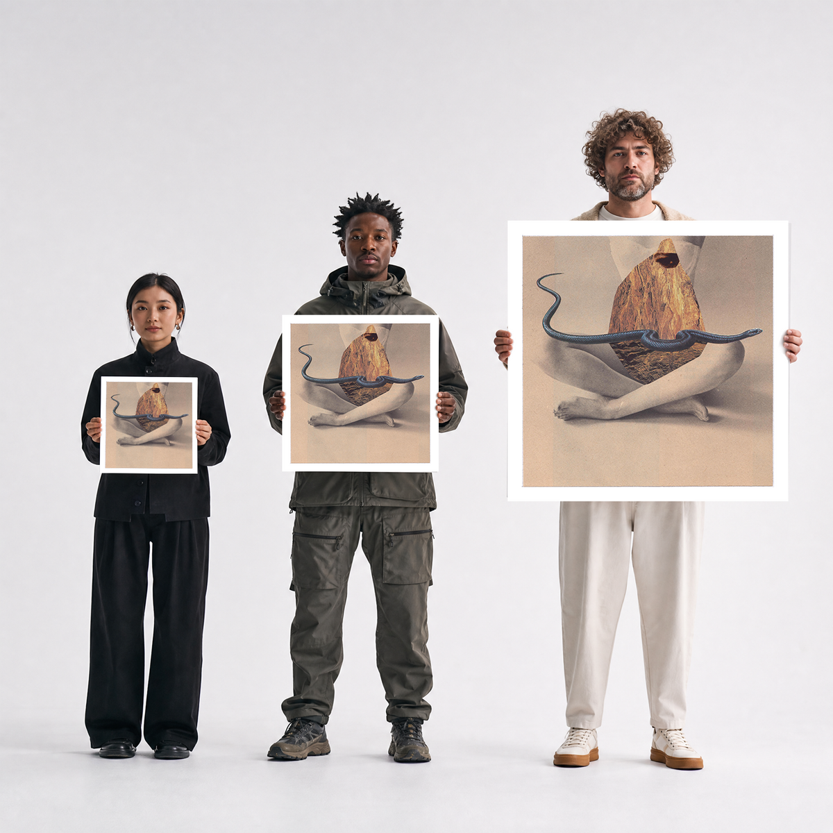 Three people standing against a light gray studio background, each holding a square art print. The prints show a surreal painting of a seated figure with a large shell-like object and a blue snake-like form.