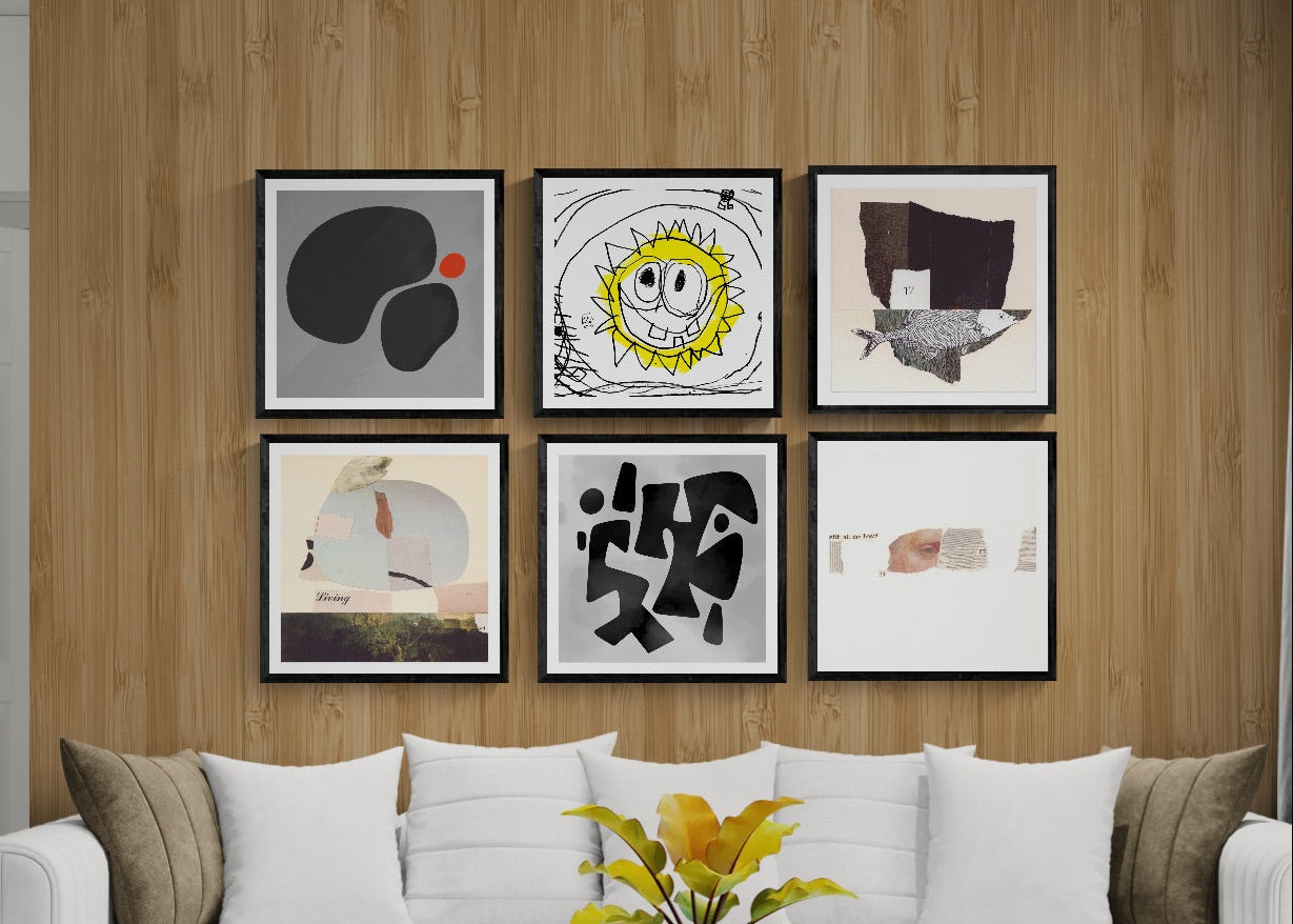 A modern living room setup featuring a 2x3 grid of six framed abstract and cartoon-style wall art prints hanging on a light brown wood-paneled wall above a white tufted sofa with decorative pillows.
